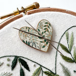 The botanical heart magnetic needle minder next to a botanical embroidery pattern