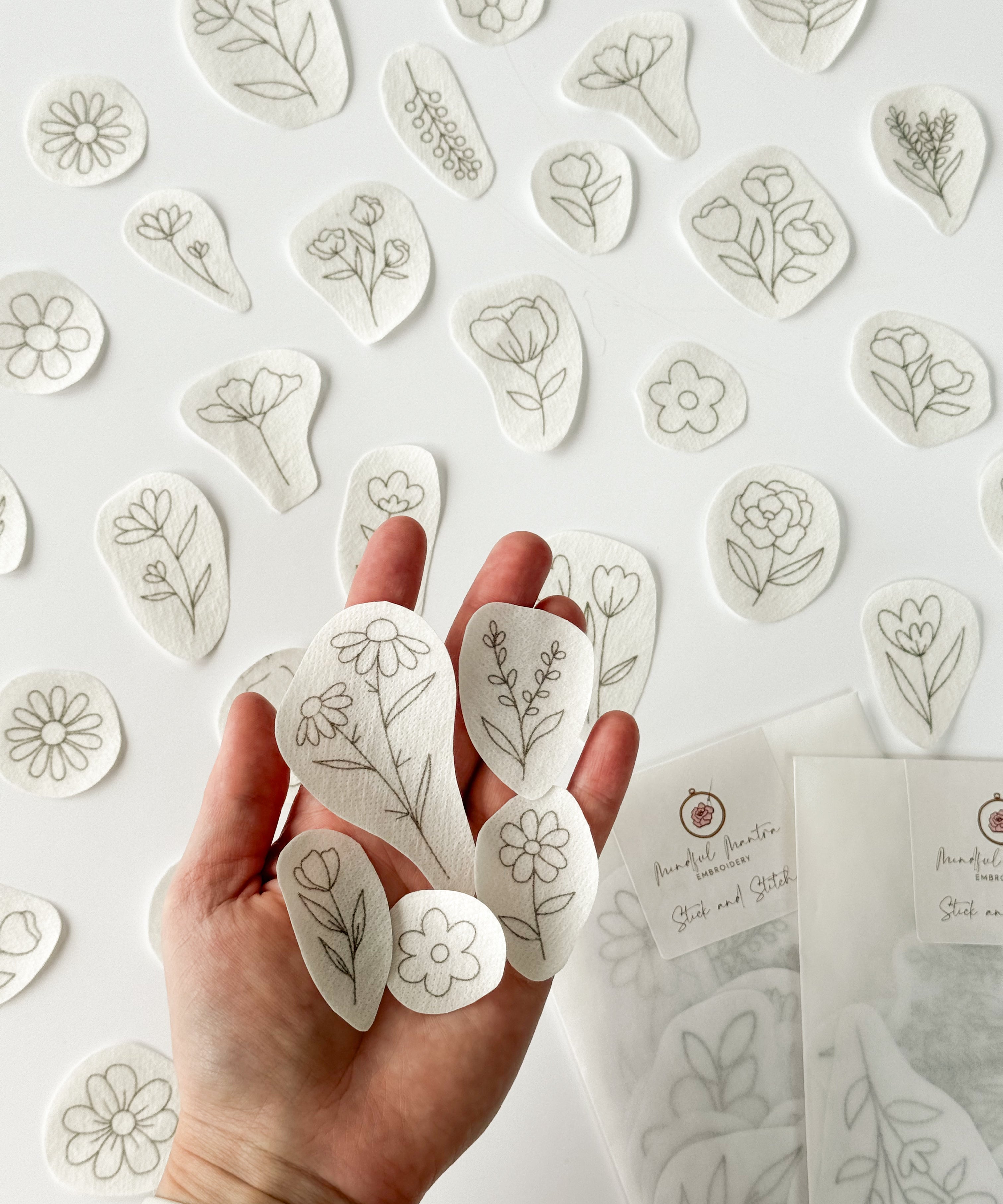 Outstretched hand holding a range of beautiful floral embroidery patterns