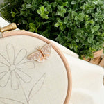 A butterfly magnetic needle minder attached to an embroidery hoop