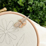 A butterfly magnetic needle minder on an embroidery hoop