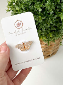 A hand holding the Butterfly Magnetic Needle Minder