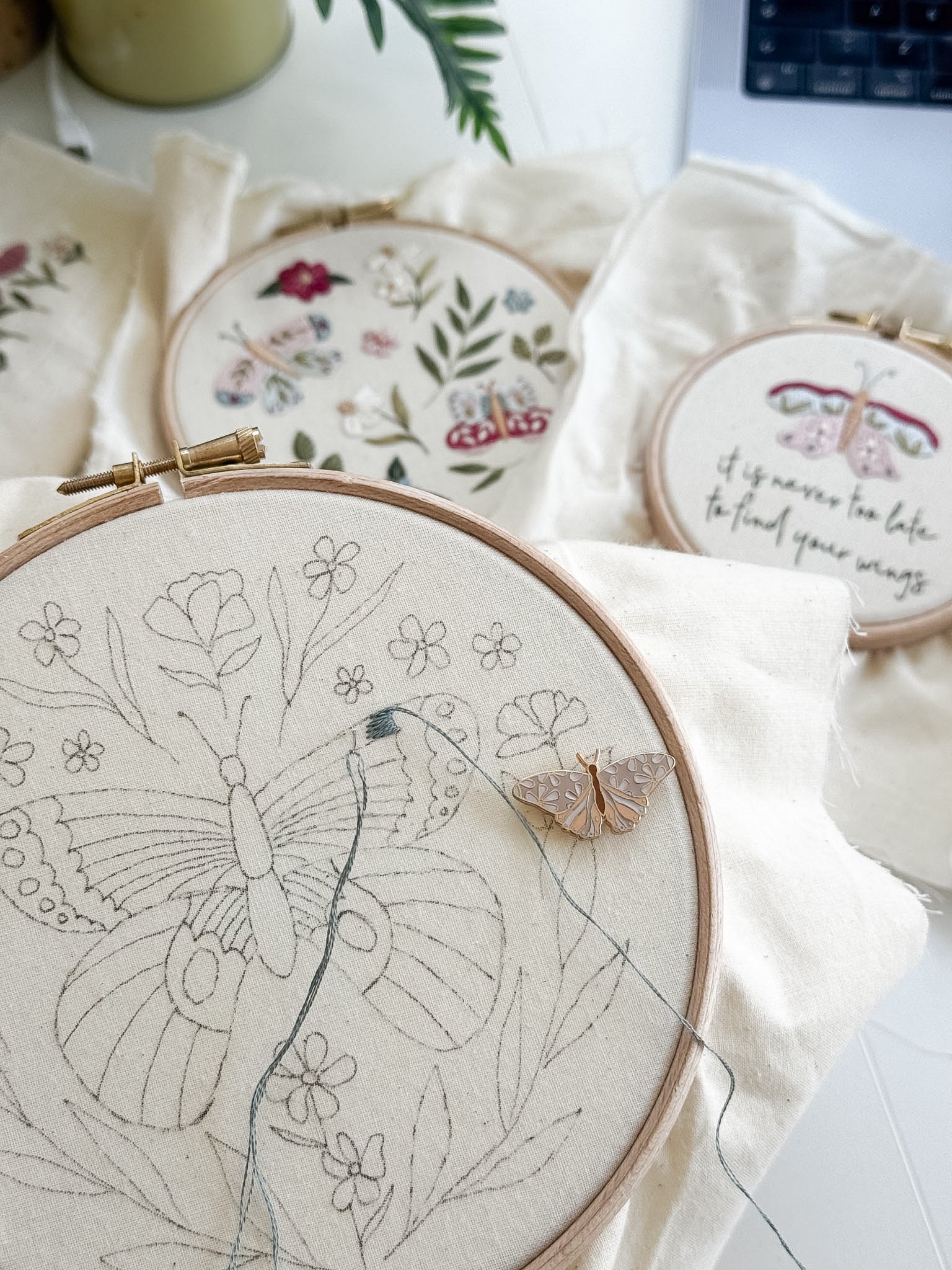 Embroidery hoops with floral and butterfly designs on a light background