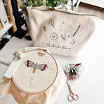 Embroidery hoop with butterfly design and project bag on a table.