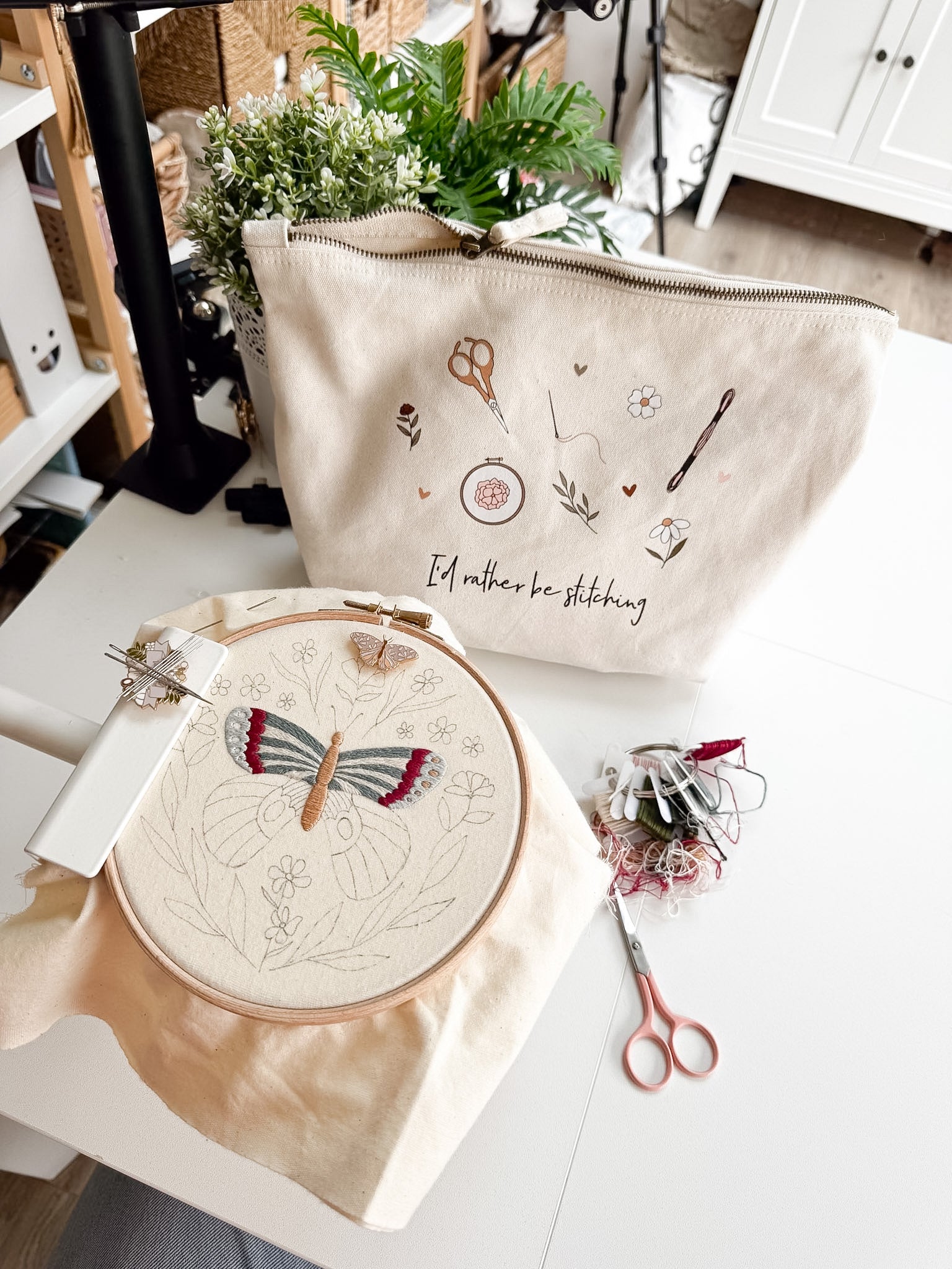 Embroidery hoop with butterfly design and project bag on a table.