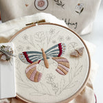 large embroidered butterfly on a hoop with a nearby butterfly needle minder