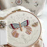 large embroidered butterfly on a hoop with a nearby butterfly needle minder