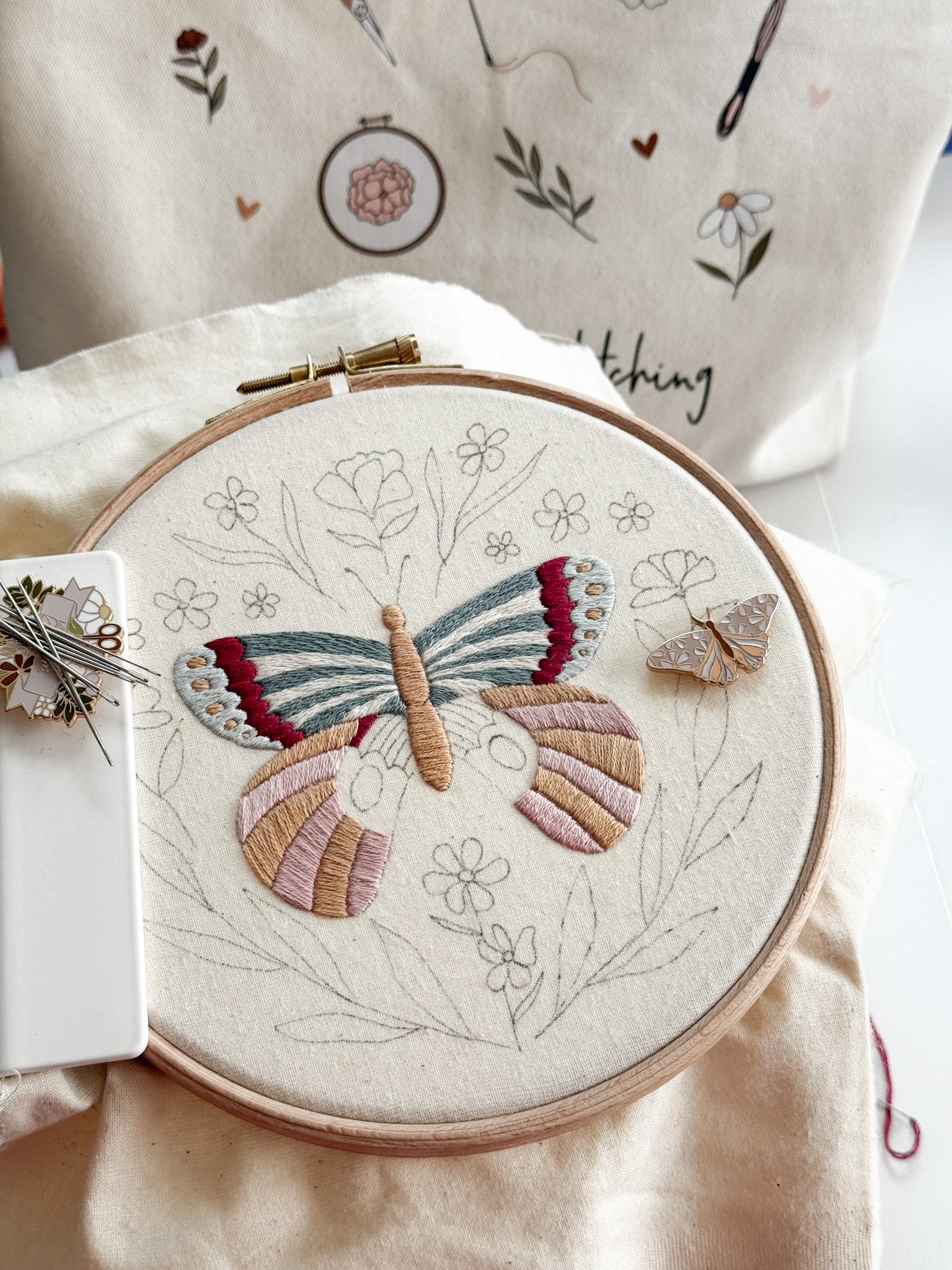 large embroidered butterfly on a hoop with a nearby butterfly needle minder