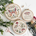 Wildflower Wings Butterfly Embroidery Pattern Bundle displayed in three hoops with floral designs and embroidery supplies.