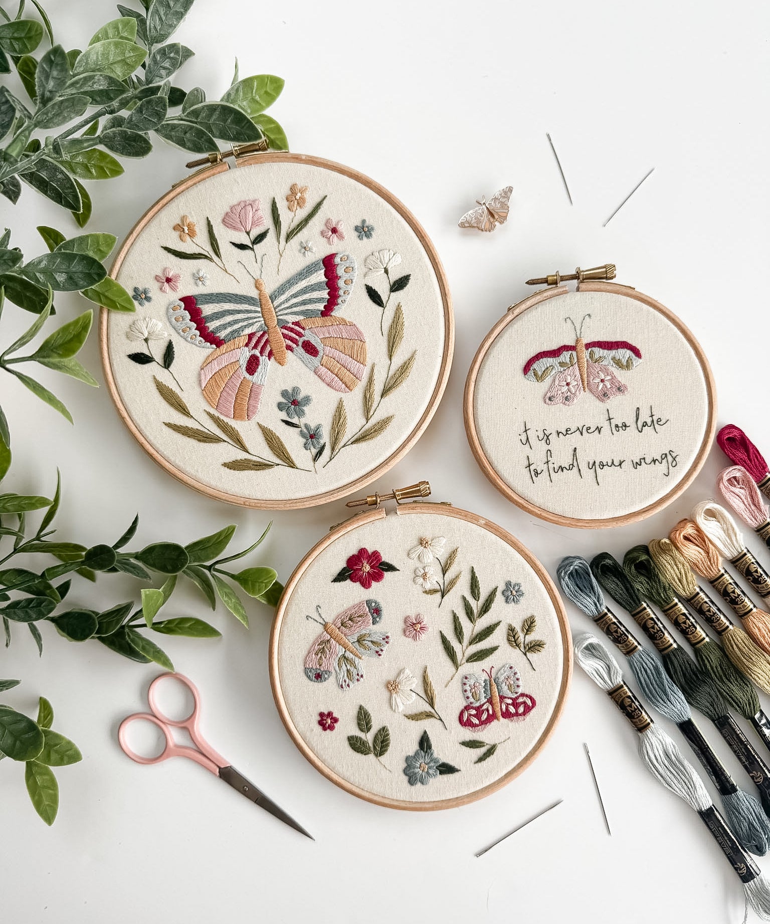 Wildflower Wings Butterfly Embroidery Pattern Bundle displayed in three hoops with floral designs and embroidery supplies.