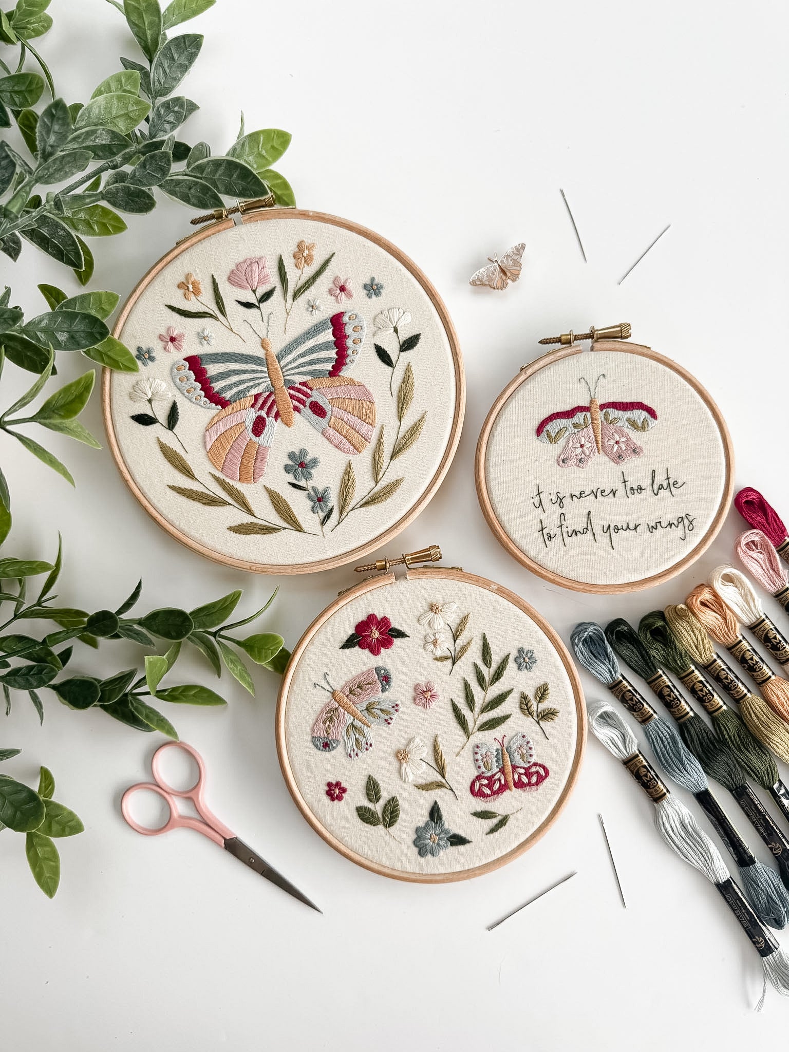 Wildflower Wings Butterfly Embroidery Pattern Bundle displayed in three hoops with floral designs and embroidery supplies.