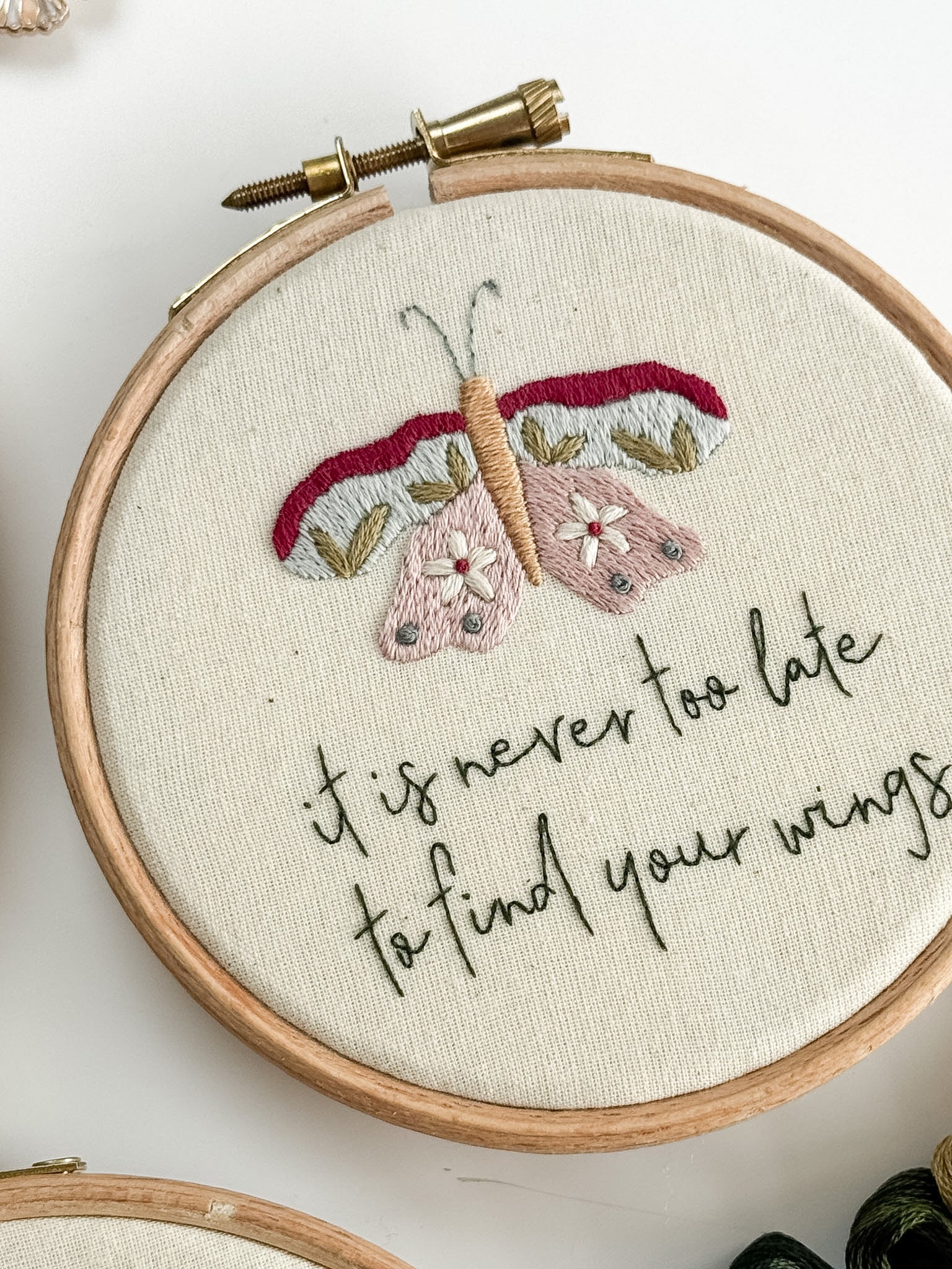 Embroidery hoop with butterfly design and motivational quote on a white background