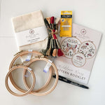 Butterfly embroidery kit with hoops, fabric, thread, and pattern book on a white background