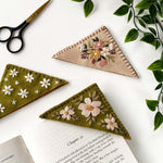 Felt bookmark embroidery kit showcasing three embroidered bookmarks on a table with scissors and greenery.
