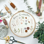 A beginner embroidery kit including a 'learn to embroider' stitch sampler. There are embroidery scissors and thread nearby.