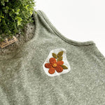 Clothes Embroidery Kit featuring a floral patch on a green tank top with lush plant backdrop.
