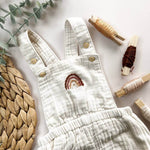 Clothes Embroidery Kit features a white romper with a rainbow stitch and surrounded by embroidery thread and natural elements.