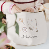 Person holding a white project bag with embroidery designs and 'I'd rather be stitching' text on a light background.