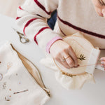 A woman stitching a pattern. Nearby is a minimalist embroidery project bag