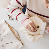 A woman stitching a pattern. Nearby is a minimalist embroidery project bag