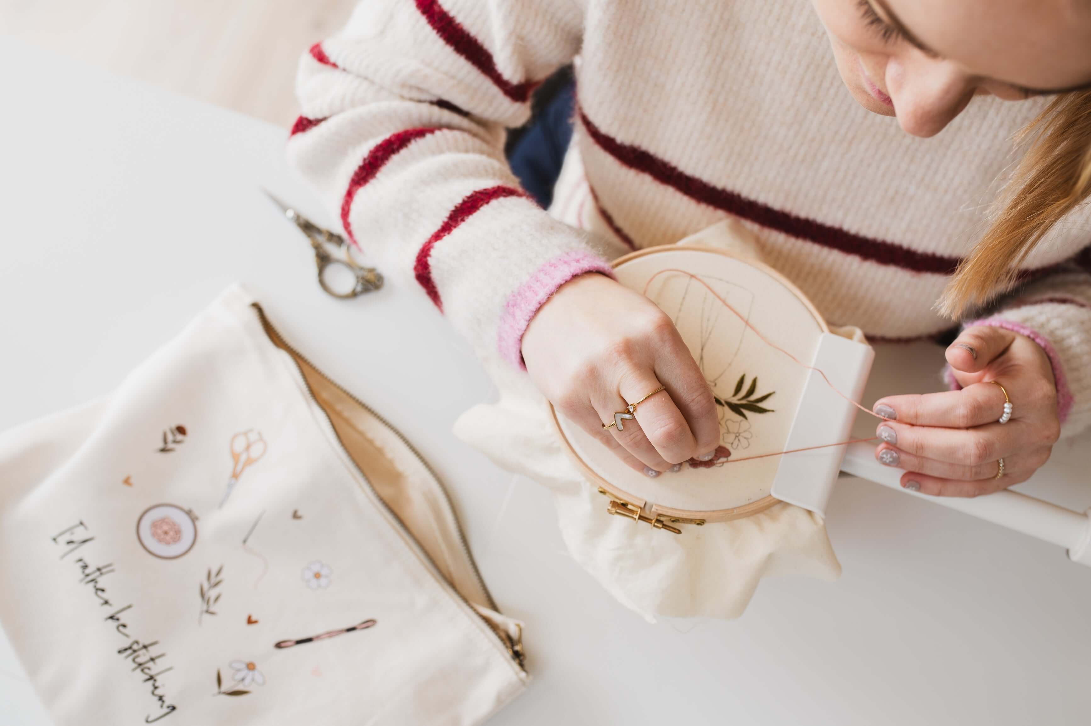 A woman stitching a pattern. Nearby is a minimalist embroidery project bag