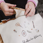 Person opening a white embroidery project bag