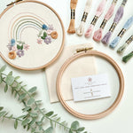 The rainbow embroidery pattern with a floral base, surrounded by thread and embroidery supplies