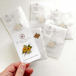 A hand holding a magnetic needle minder with a sunflower pattern