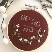 Holly embroidery pattern stitched on red fabric.