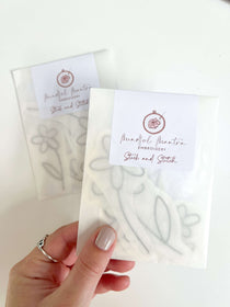 A hand holding a pack of daisy stick and stitch embroidery patterns
